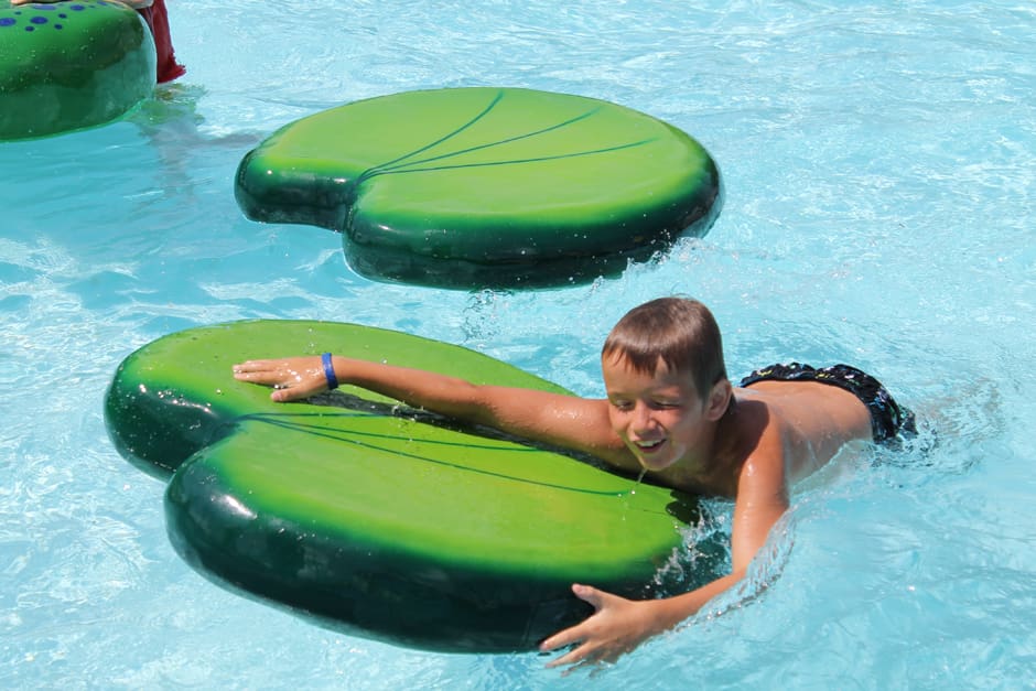 water park floatables, boy climbing onto big lily pad