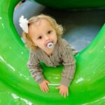 toddler age girl playing on soft play playground