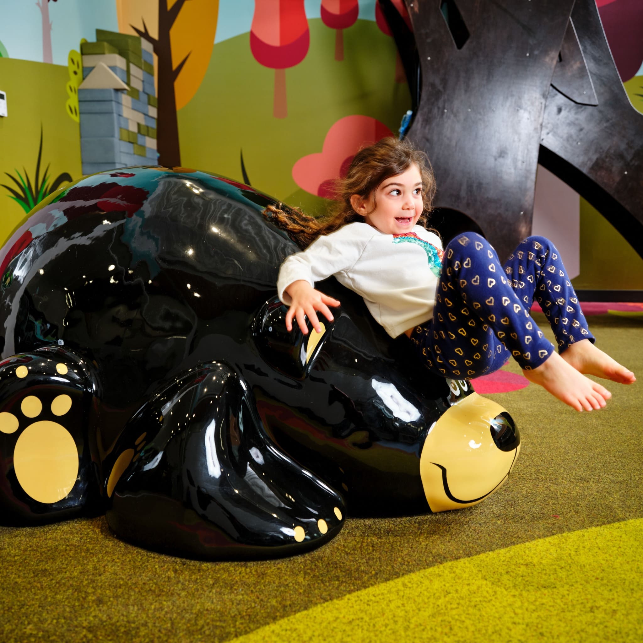 girl sliding down a Toonie bear, playground soft sculpture