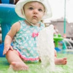 baby sitting on a soft play splash pad