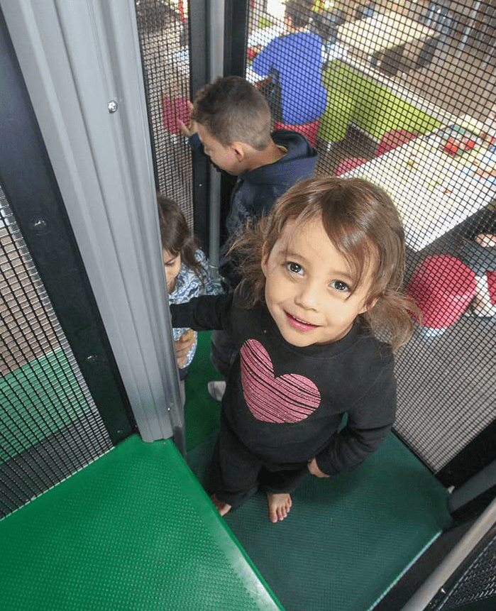 A child smiles while playing in a play structure